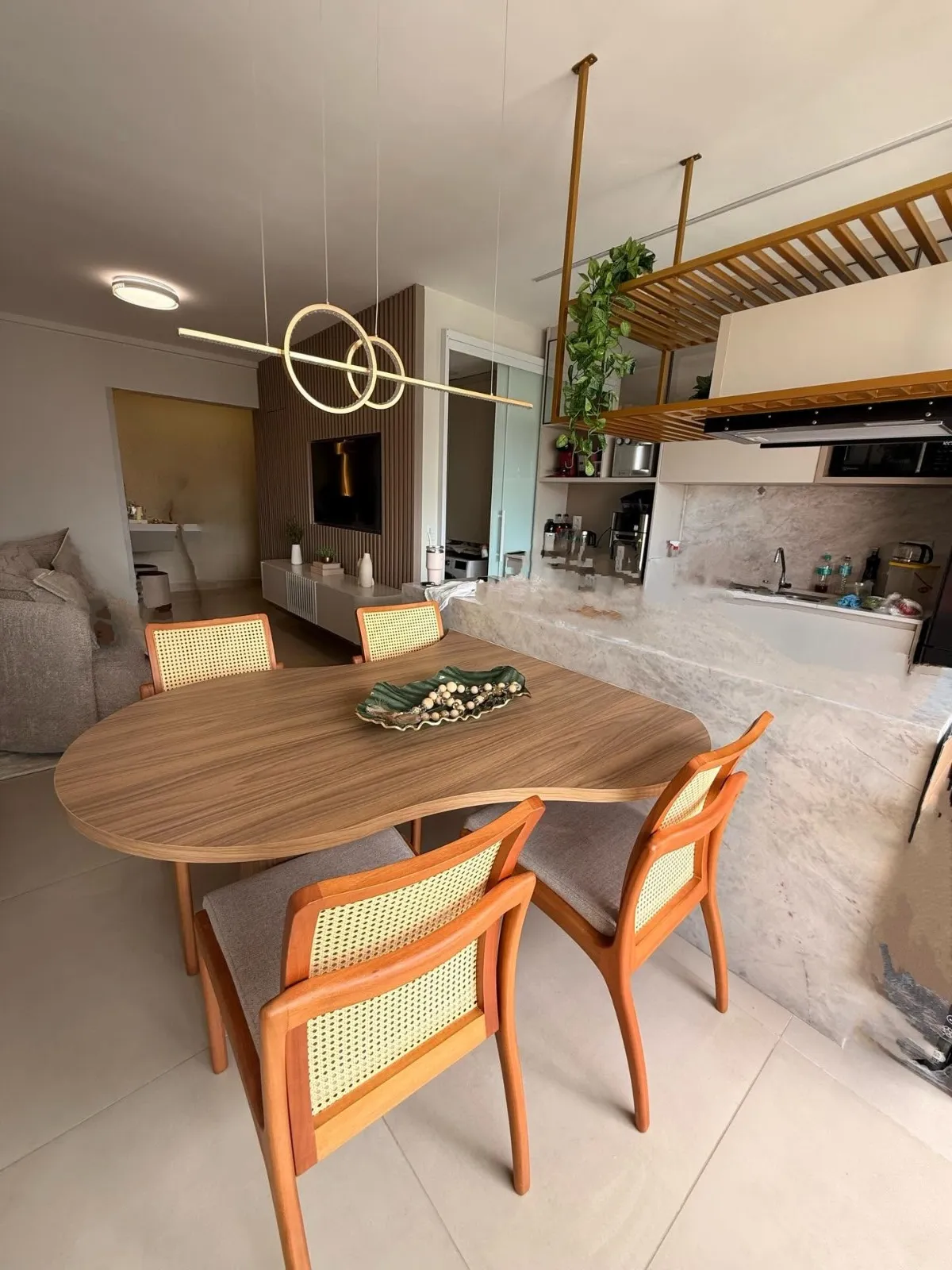 Ambiente integrado com mesa, painel de televisão e cozinha planejada