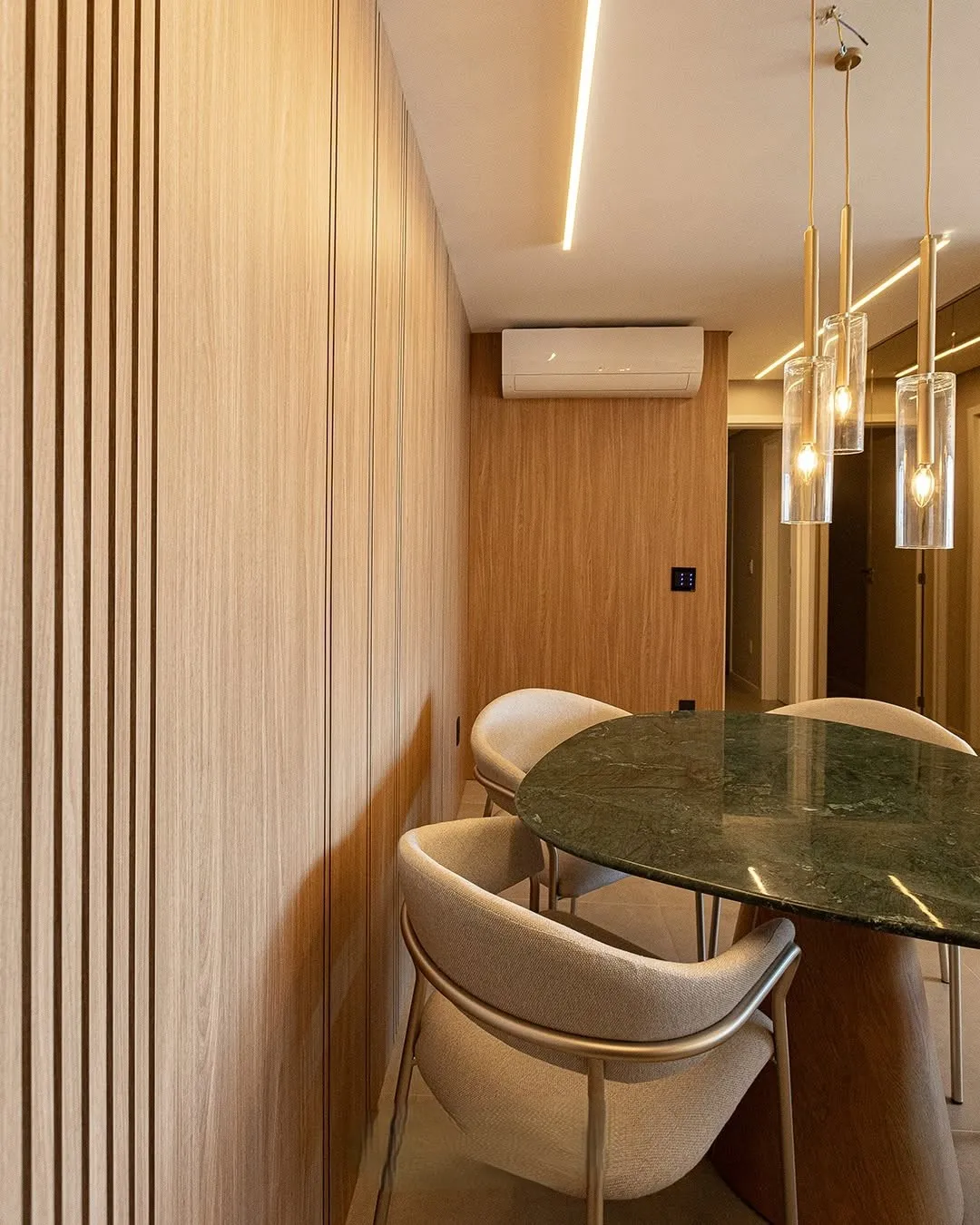 Sala de jantar com painel ripado e marcenaria em tom amadeirado